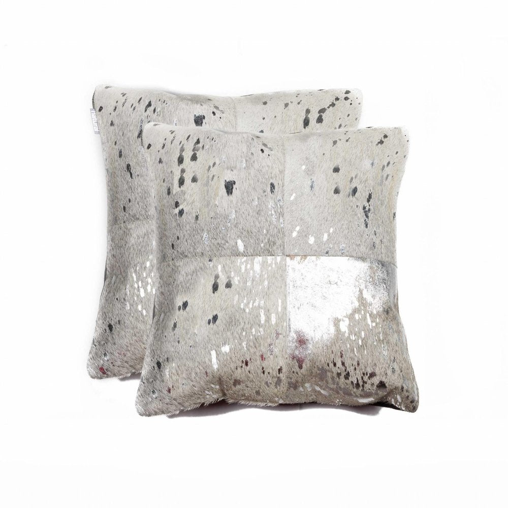 Two square throw pillows made of silver and gray cowhide with black spots, on a white background.