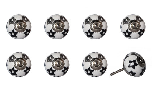 Eight white ceramic cabinet knobs with black star pattern and silver metal hardware on a white background.