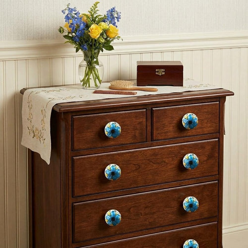 Brown wooden dresser with blue, black, and yellow floral ceramic knobs, a vase of flowers, and a wooden box on top.