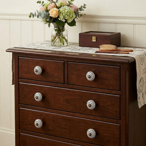1.5" X 1.5" X 1.5" Hues Of Bronze White And Black Knobs 8 Pack installed on a dark wood dresser in a furnished interior with a cream wall.