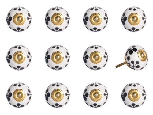 Twelve white ceramic cabinet knobs with black floral pattern and gold center on a white background.