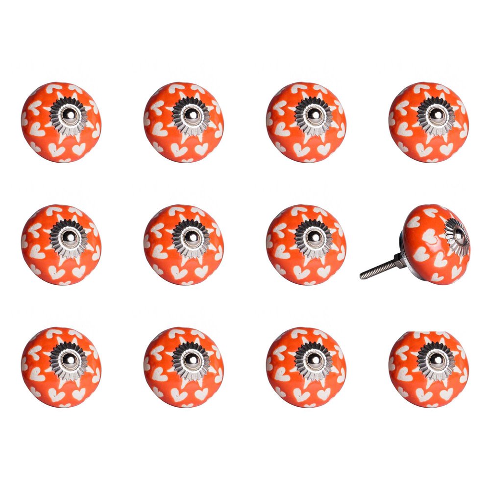 Twelve orange ceramic drawer knobs with white hearts and silver floral accents on a white background.