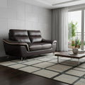69" Brown And Silver Faux Leather Love Seat styled in a furnished interior on a charcoal floor against a light gray wall.