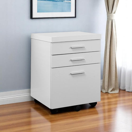White particle board filing cabinet with three drawers and silver handles on black wheels in a room with a blue wall and curtains.