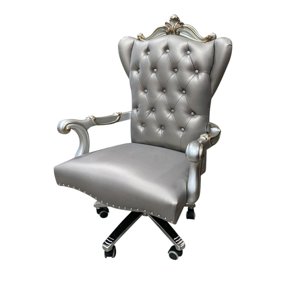 Gray faux leather tufted executive chair with silver ornate accents and a five-wheel base on a white background.