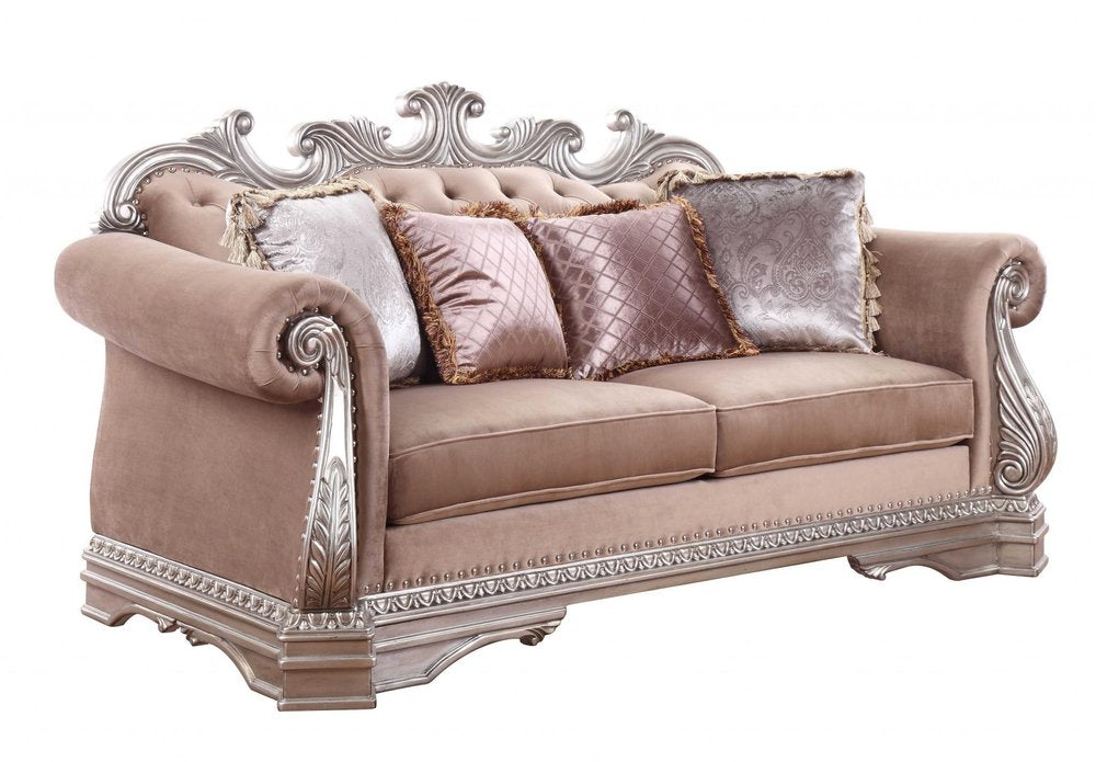 Champagne velour loveseat with ornate silver trim and decorative toss pillows on a white background.