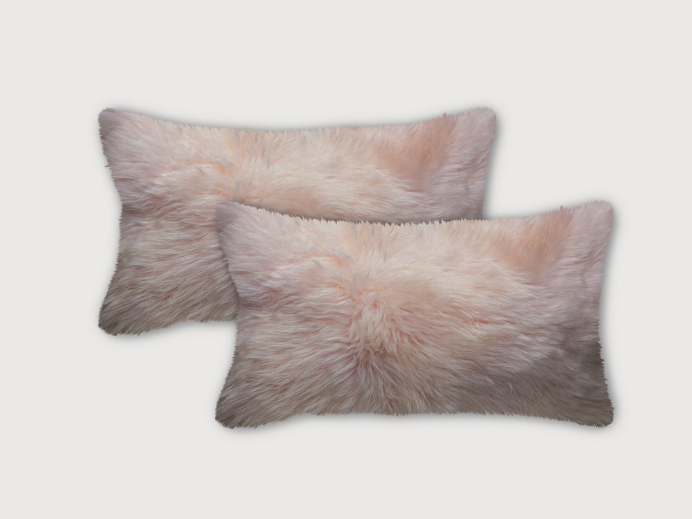 Two blush pink sheepskin lumbar accent pillows on a light gray background.