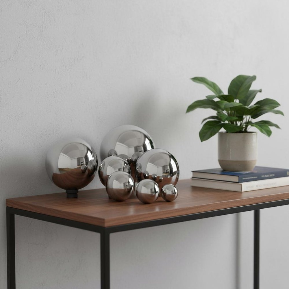 6" X 6" X 6" Buffed Polished Sphere displayed on a tabletop in a furnished interior against a light gray wall in silver metal.
