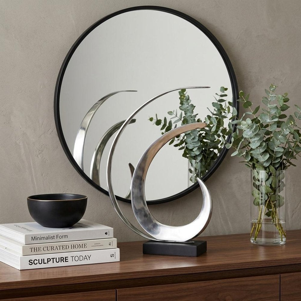 18" Black and Silver Buffed Aluminum Tabletop Sculpture styled in a furnished interior with a tan wall on a dark wood floor.