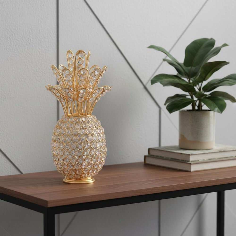 13" Gold and Faux Crystal Pineapple Tabletop Sculpture styled in a furnished interior with a light gray wall on a charcoal floor.