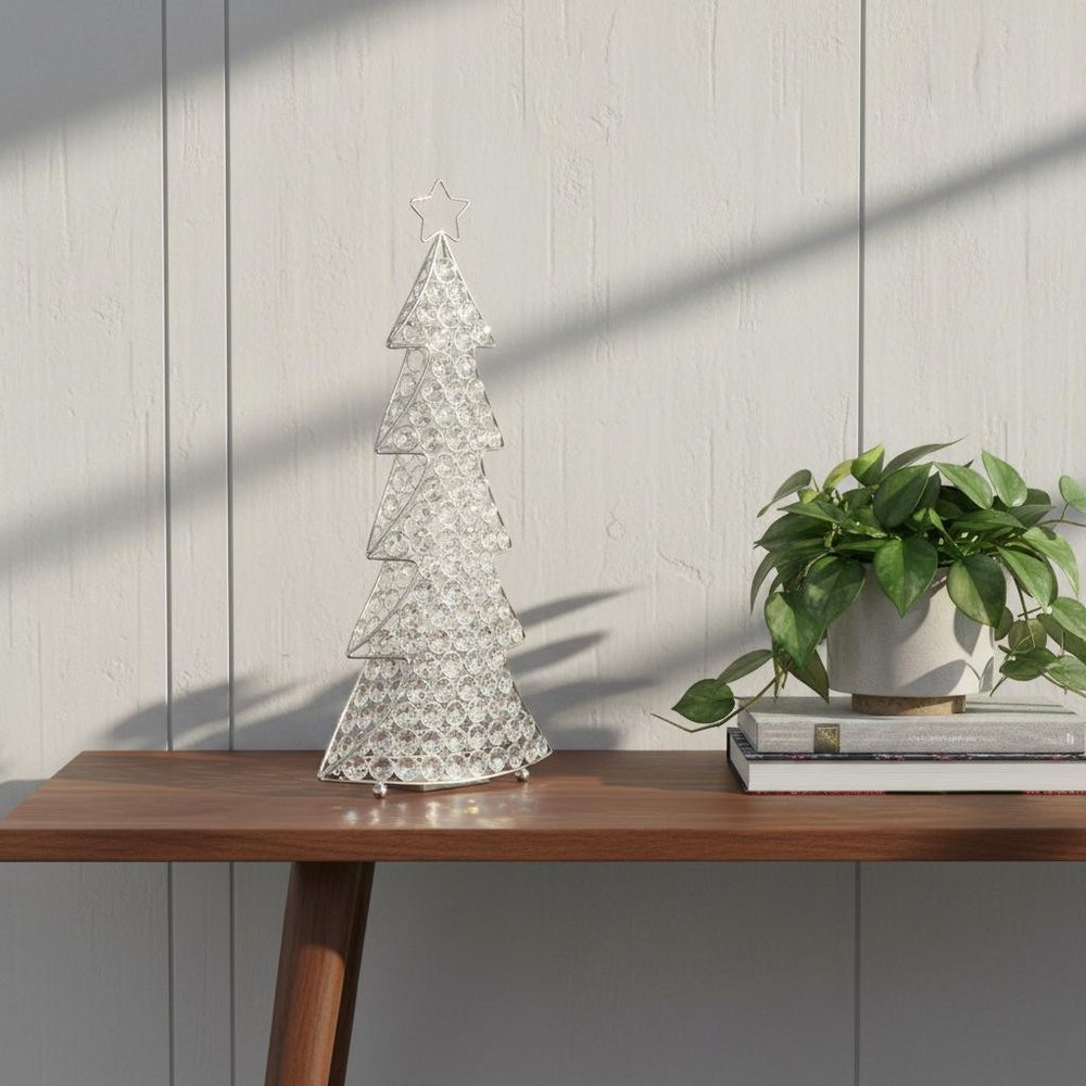 16" Glam Silver And Faux Crystals Christmas Tree Tabletop Sculpture styled in a furnished interior with an off-white wall on a tiled floor.