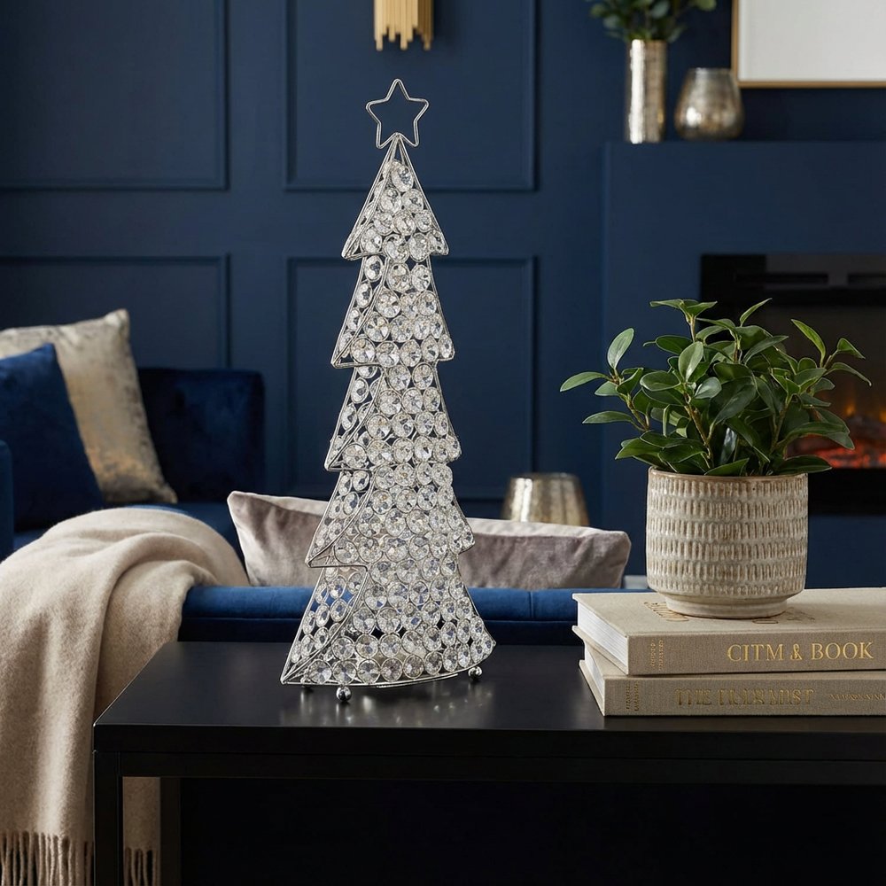 16" Glam Silver And Faux Crystals Christmas Tree Tabletop Sculpture styled in a furnished interior with a navy wall on a black floor.