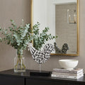 11" Black and Silver Aluminum Tabletop Sculpture styled in a furnished interior with a tan wall on a black floor.