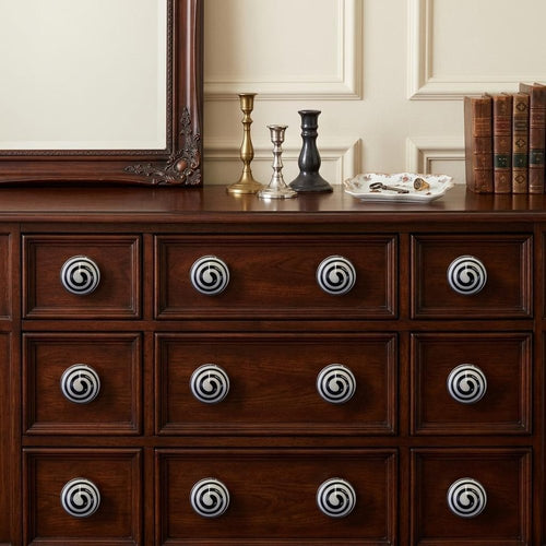 1.5" X 1.5" X 1.5" Ceramic Metal Multicolor 12 Pack Knob installed on a wood dresser in a furnished interior with a cream wall in black ceramic.