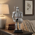 17" Silver Metal Hand Painted Figurine Tabletop Sculpture styled in a furnished interior with a brown wall on a dark wood floor.