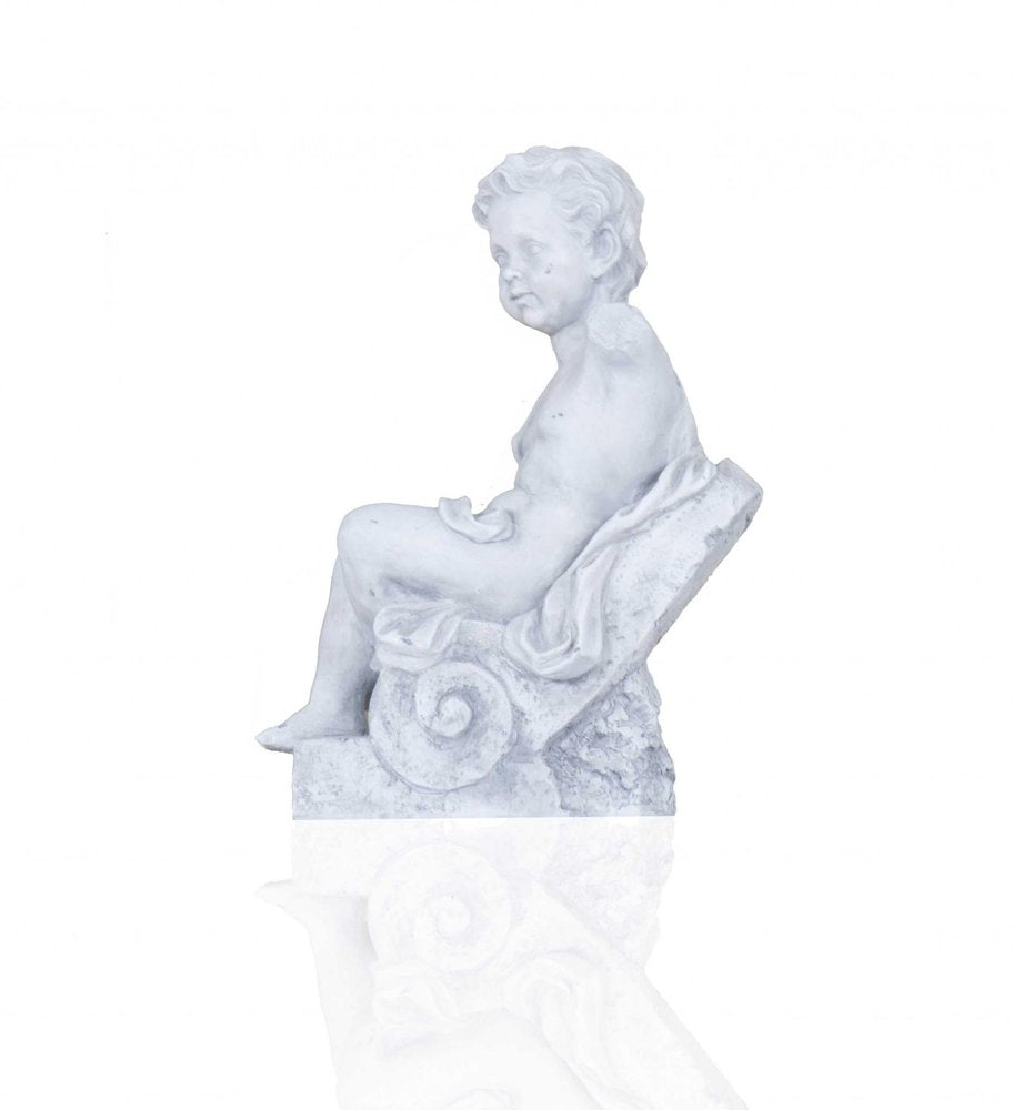 White plaster statue of a boy sitting on a decorative base with a reflection on a white background.