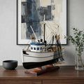 22" Black And White Solid Wood Hand Painted Model Boat styled in a furnished interior with a light gray wall on a dark wood floor.