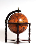 A vintage-style globe bar with an orange map and dark wood stand against a white background.
