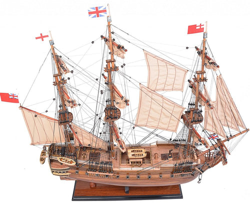 A detailed brown solid wood model ship with sails and flags on a white background.