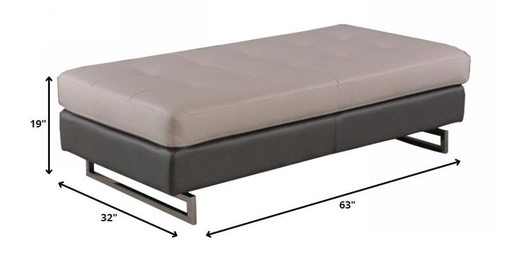 63" Taupe Brown and Silver Faux Leather Tufted Ottoman. Ottoman isolated on a plain white background, showing a taupe faux leather surface.
