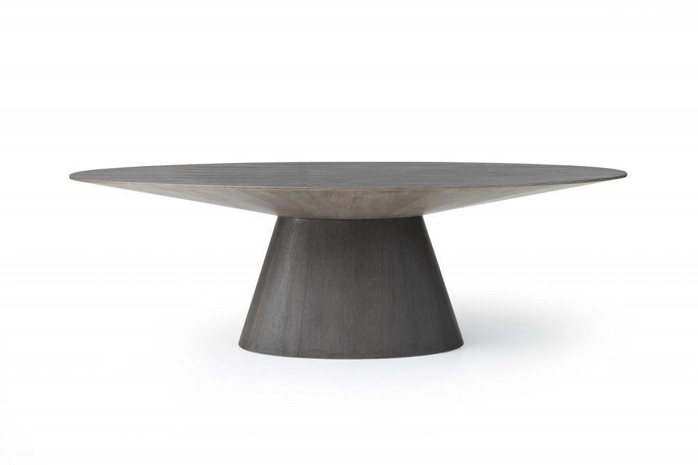 A gray solid wood dining table with a rounded top and a tapered pedestal base on a white background.