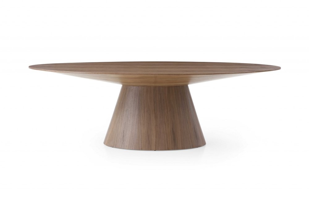 Brown oval solid wood dining table with a pedestal base on a white background.