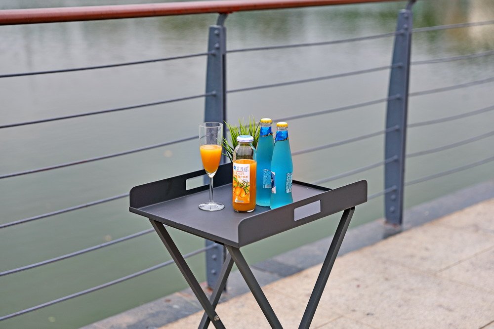 19" Gray Aluminum Outdoor Side Table styled in a furnished interior with a gray wall on a tiled floor.