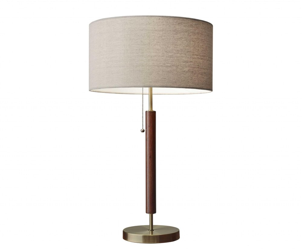 26" Antiqued Brass Solid Wood Table Lamp With Beige Drum Shade. Table lamp isolated on a plain white background, showing a beige wood surface.
