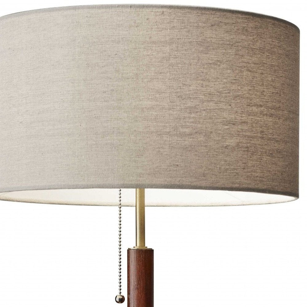 26" Antiqued Brass Solid Wood Table Lamp With Beige Drum Shade. Table lamp isolated on a plain white background, showing a beige wood surface.