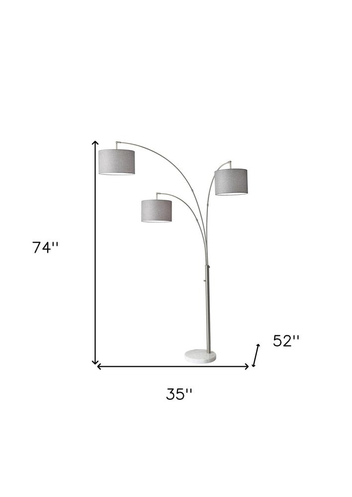 74" Brass Three Light Arc Floor Lamp With Off White Fabric Drum Shade on a white background