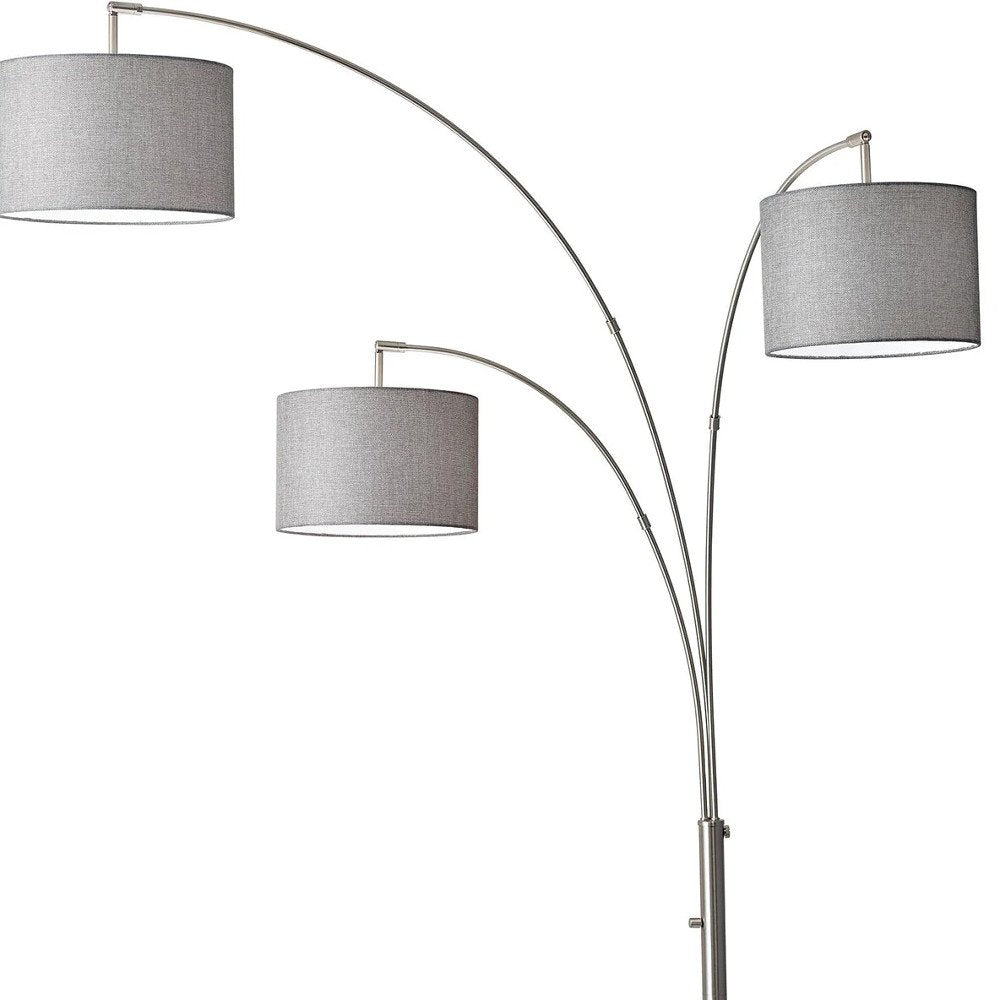 74" Brass Three Light Arc Floor Lamp With Off White Fabric Drum Shade on a white background