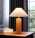 26" Natural Solid Wood Cylinder Table Lamp With White Cone Shade shown outdoors on an outdoor setting with greenery.