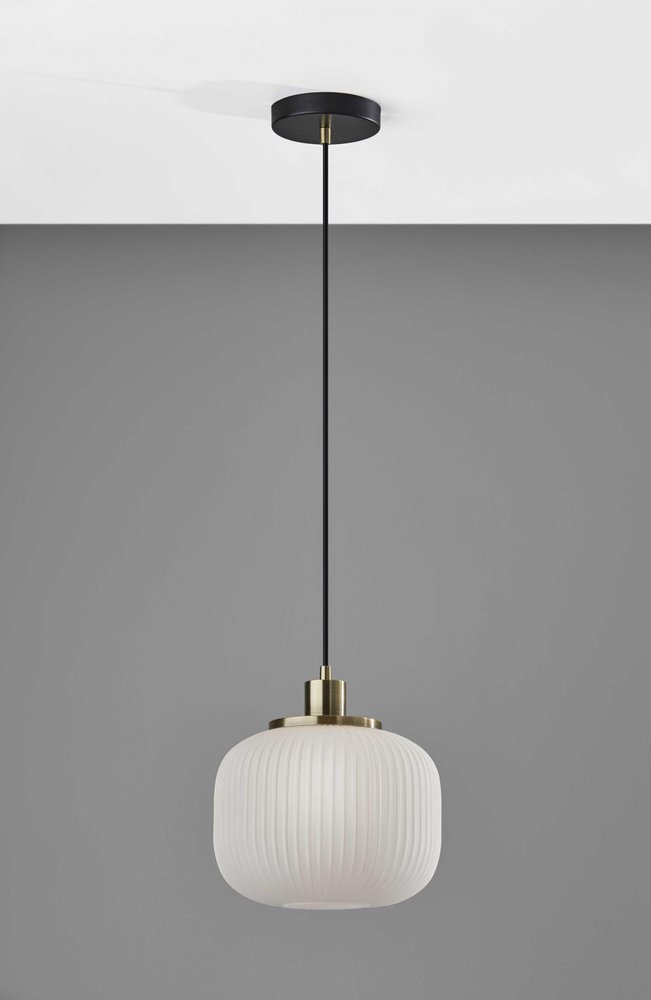 A ribbed white glass pendant light with brass accents hangs from a black cord against a grey background.