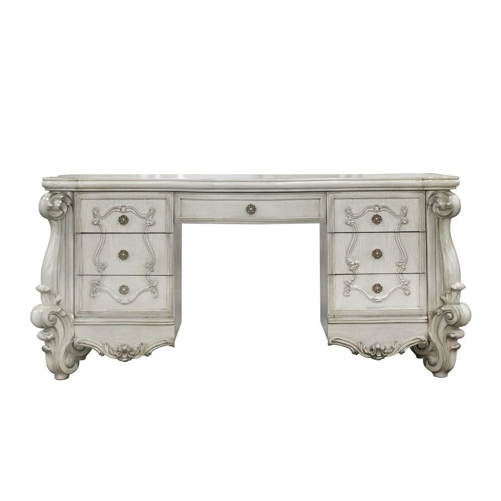 Antiqued white wood vanity table with seven drawers and ornate detailing on a white background.