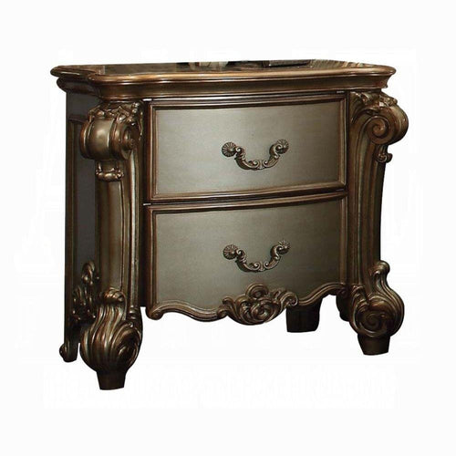 A bone wood two-drawer nightstand with ornate carvings and antique brass hardware on a white background.