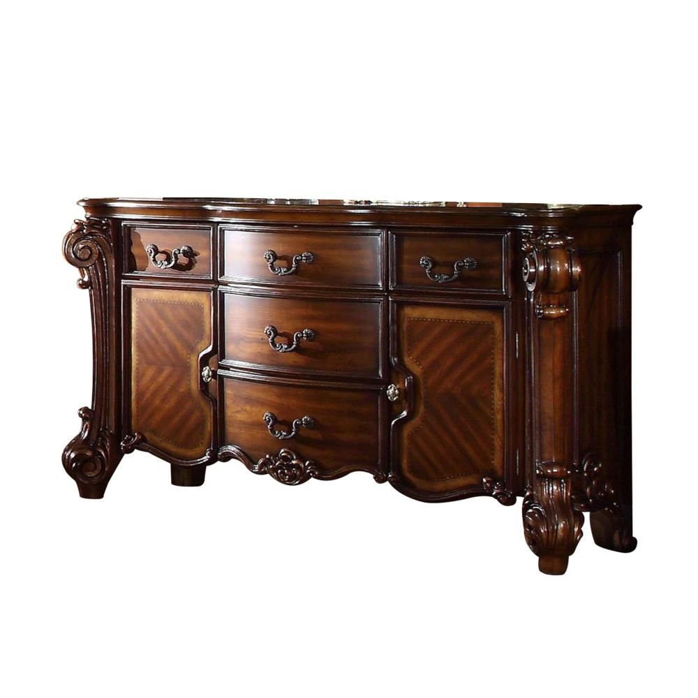 A dark brown solid wood dresser with ornate carvings and five drawers, set against a white background.