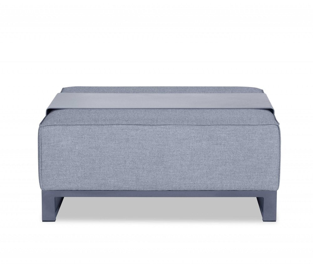Gray linen upholstered ottoman with a gray tray on top, set against a white background.