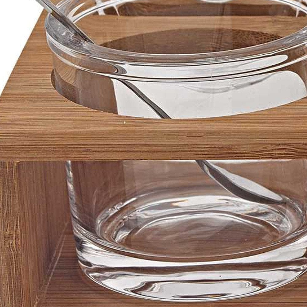 6 Mouth Blown Crystal Jam Set With 3 Glass Jars And Spoons On A Wood Stand styled in a furnished interior with a dark brown wall on a dark wood floor.