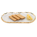 Clear glass oval platter with gold leaf edge, holding three crackers and a wedge of Swiss cheese on a white background.
