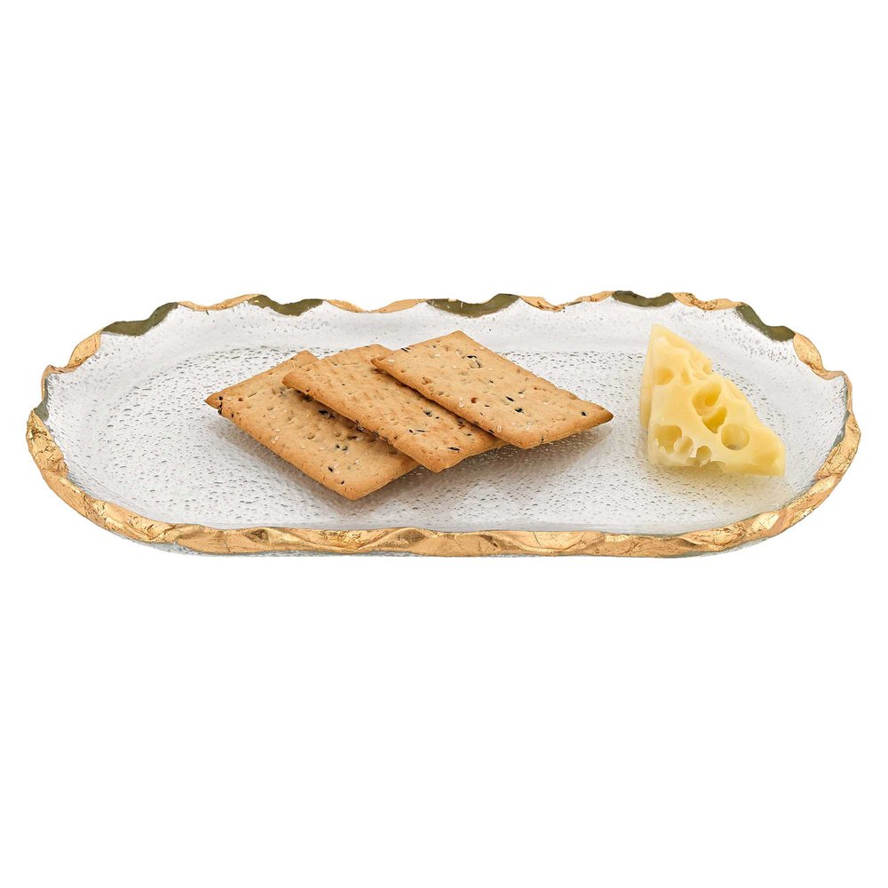 Clear glass oval platter with gold leaf edge, holding three crackers and a wedge of Swiss cheese on a white background.