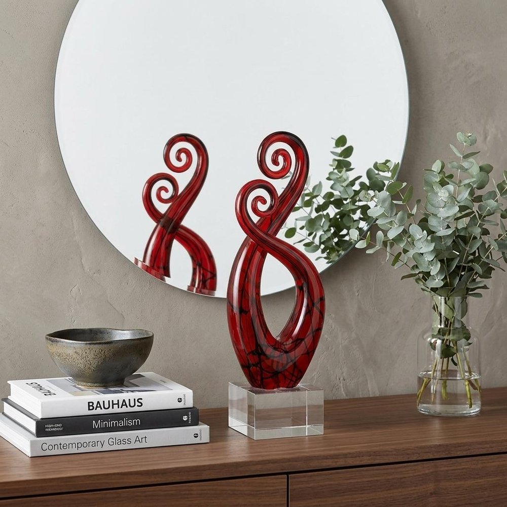 13" Clear Burgundy and Black Murano Glass Modern Abstract Tabletop Sculpture styled in a furnished interior with an off-white wall on a dark wood floor.