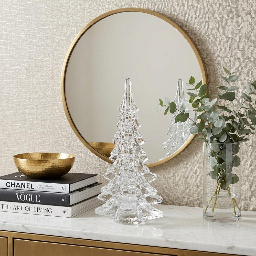 10" Mouth Blown Clear Glass Christmas Tree Sculpture styled in a furnished interior with an off-white wall on a off-white floor.
