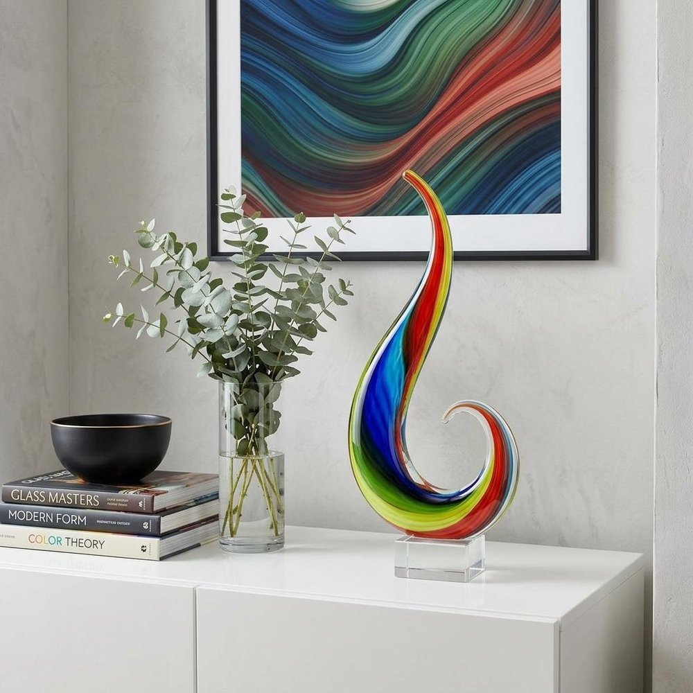 12" Clear Red Blue Yellow Murano Glass Modern Abstract Tabletop Sculpture styled in a furnished interior with a gray wall on a off-white floor.