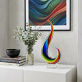 12" Clear Red Blue Yellow Murano Glass Modern Abstract Tabletop Sculpture styled in a furnished interior with a gray wall on a off-white floor.