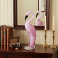 15" Pink Murano Glass Flamingo Figurine Tabletop Sculpture styled in a furnished interior with a cream wall on a black floor.
