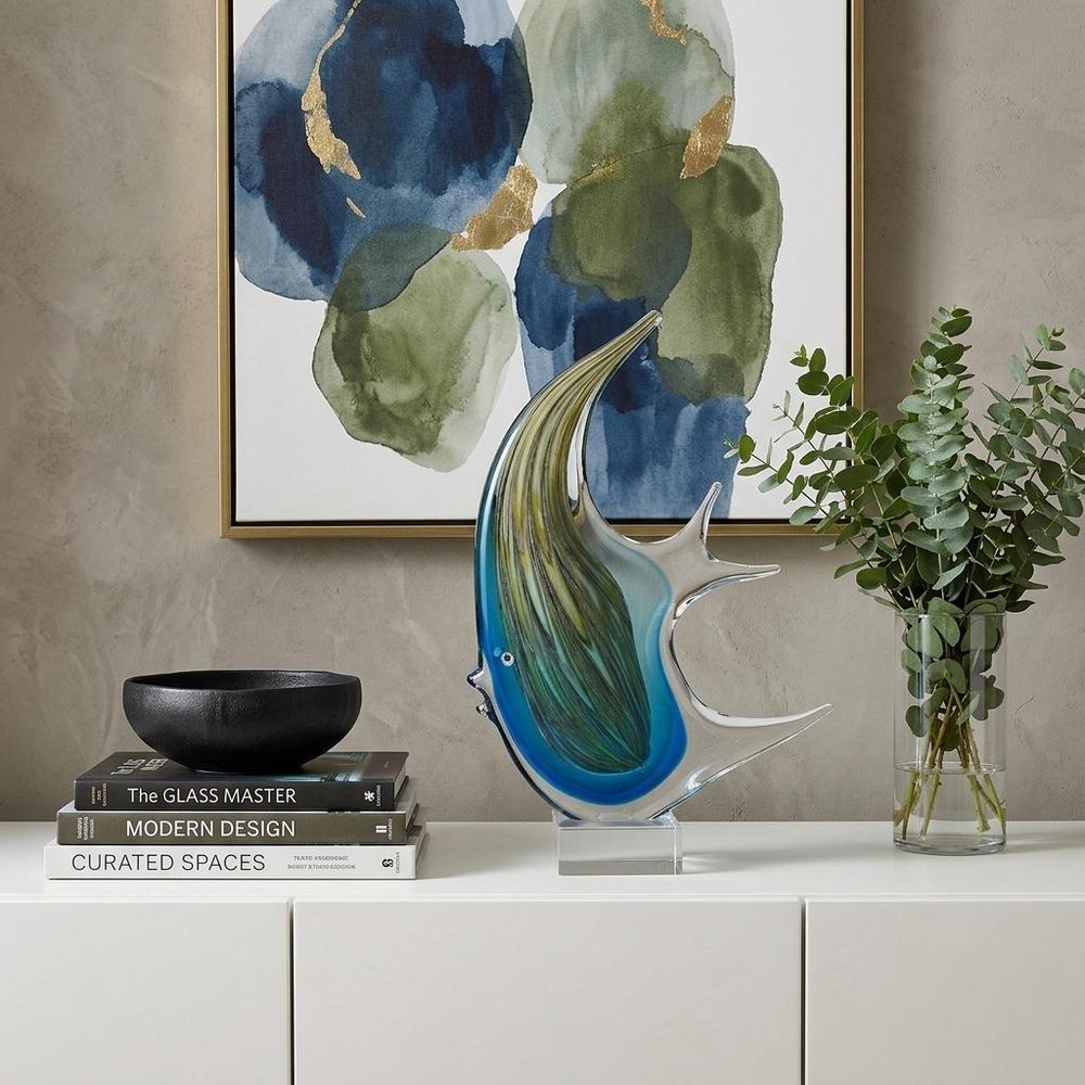 17" Blue Murano Glass Fish Figurine Tabletop Sculpture styled in a furnished interior with a tan wall on a off-white floor.