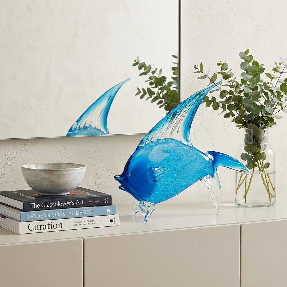 16" Blue Murano Glass Fish Figurine Tabletop Sculpture styled in a furnished interior with an off-white wall on a wood floor.