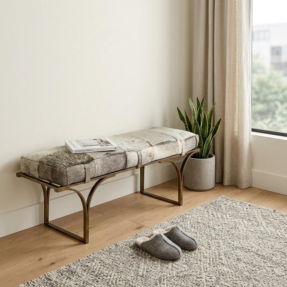 55" Gray and Antiqued Brass Faux Fur Upholstery Bench styled in a furnished interior with an off-white wall on a wood floor.