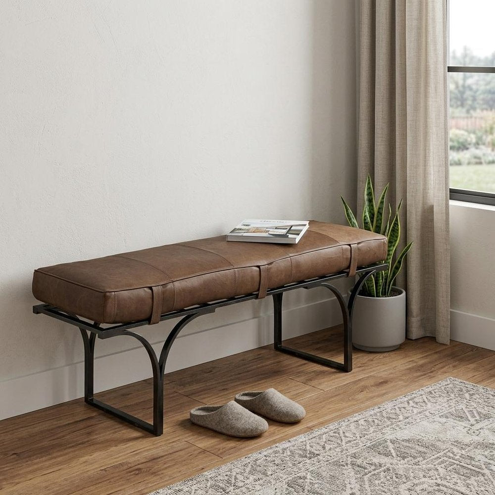 55" Brown and Black Genuine Leather Upholstery Bench styled in a furnished interior with an off-white wall on a wood floor.