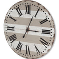 Gray and white striped metal analog wall clock with Roman numerals on a white background.